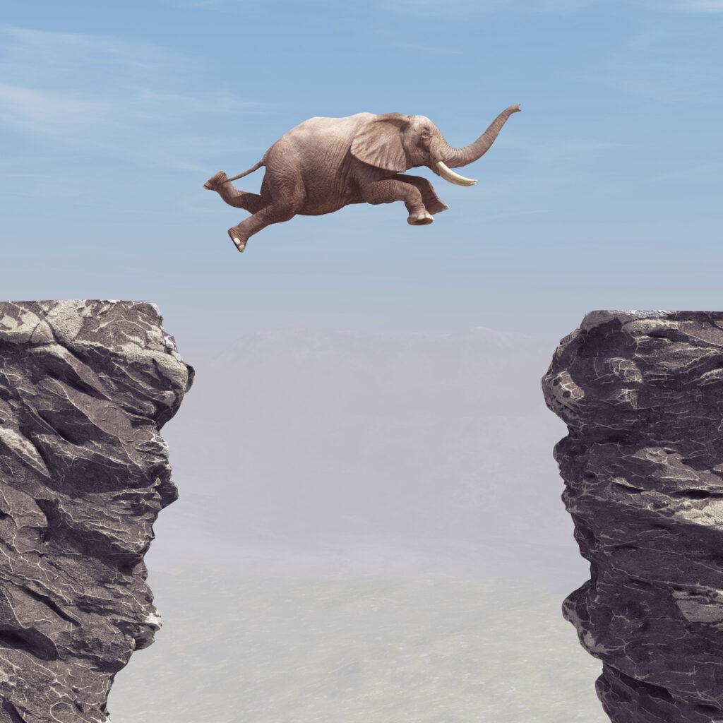 Elefant springt von einem Felsen zu einem anderen Felsen, in Leichtigkeit Unmögliches schaffen