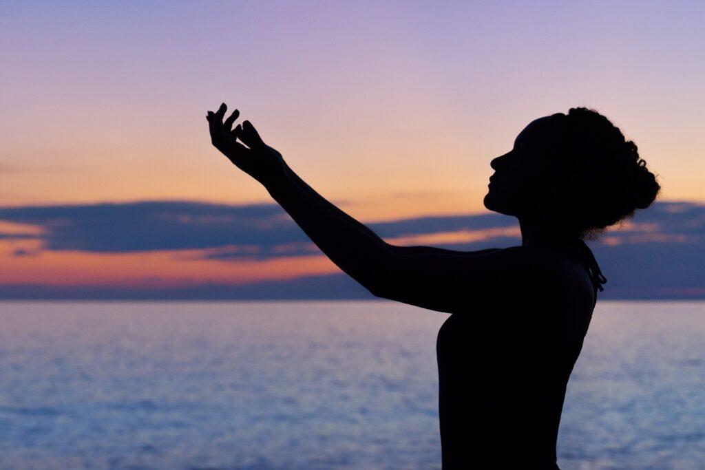 Silhouette einer Dame mit Armen gegen den Himmel gerichtet, Ruhe, Gelassenheit, innerer Frieden, Weisheit