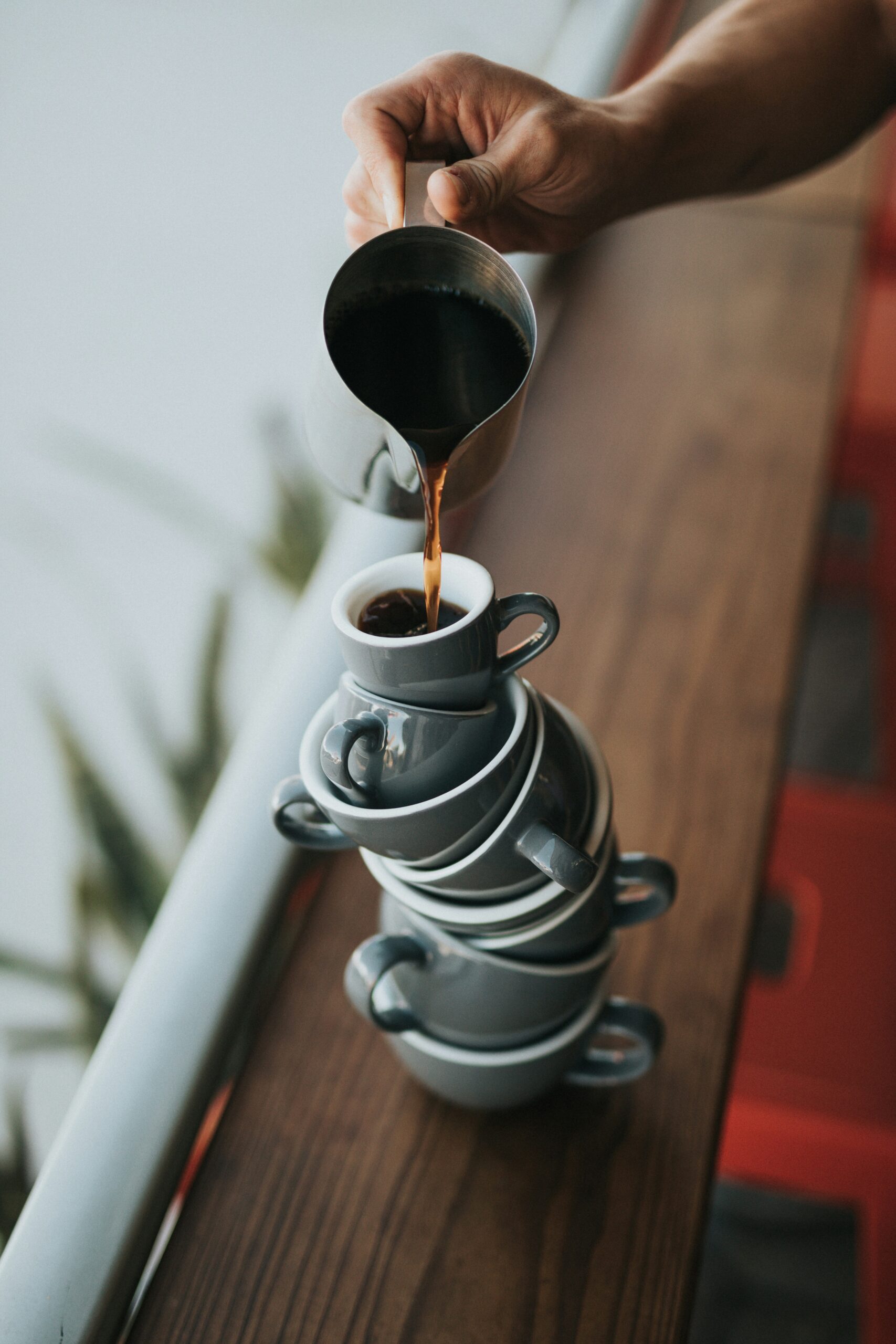 Kaffee wird ruhig in aufeinander gestapelte Tassen gegossen – Sinnbild für Balance, innere Ordnung und bewusste Selbstführung.
